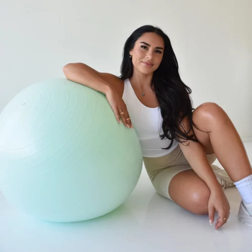 Elif from Her Wellness Co sitting and leaning on exercise ball